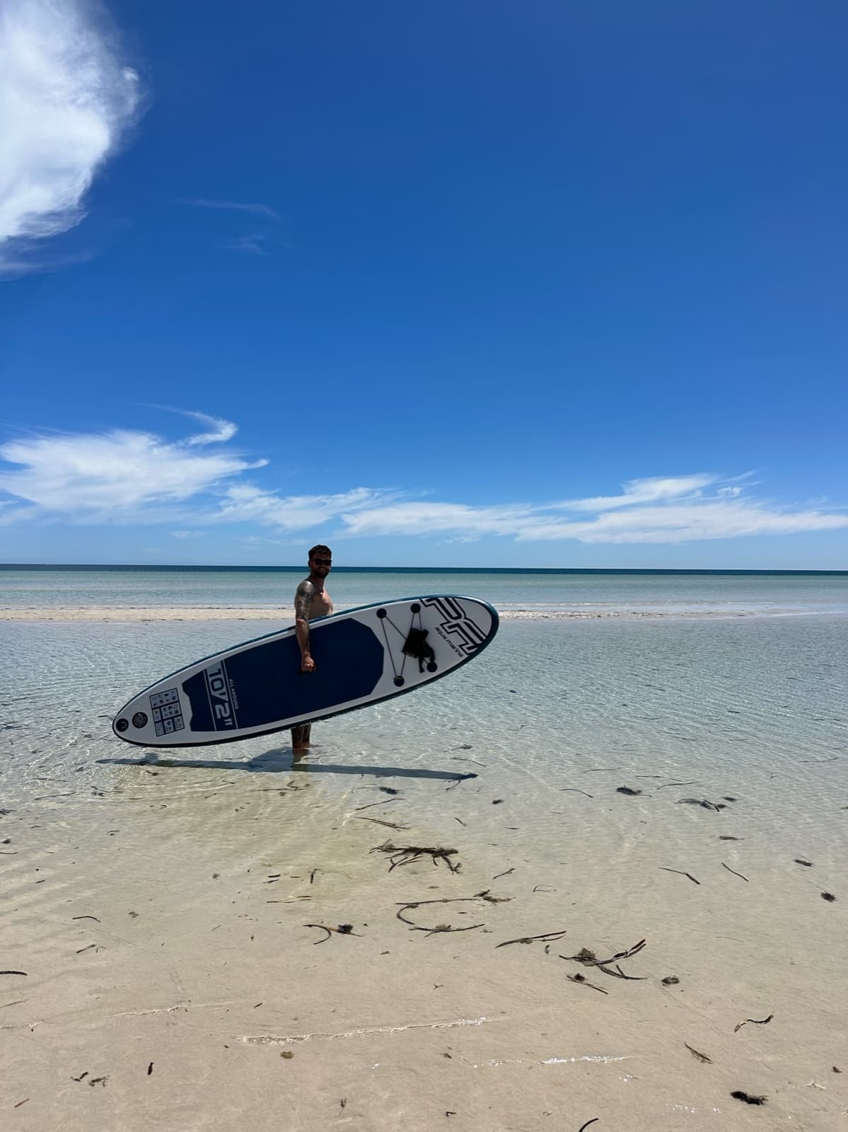 Persona amb una taula de surf de rem al costat del mar