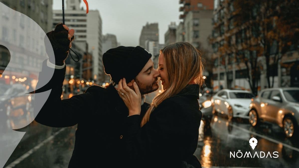 Pareja besándose bajo un paraguas en una calle de la ciudad.
